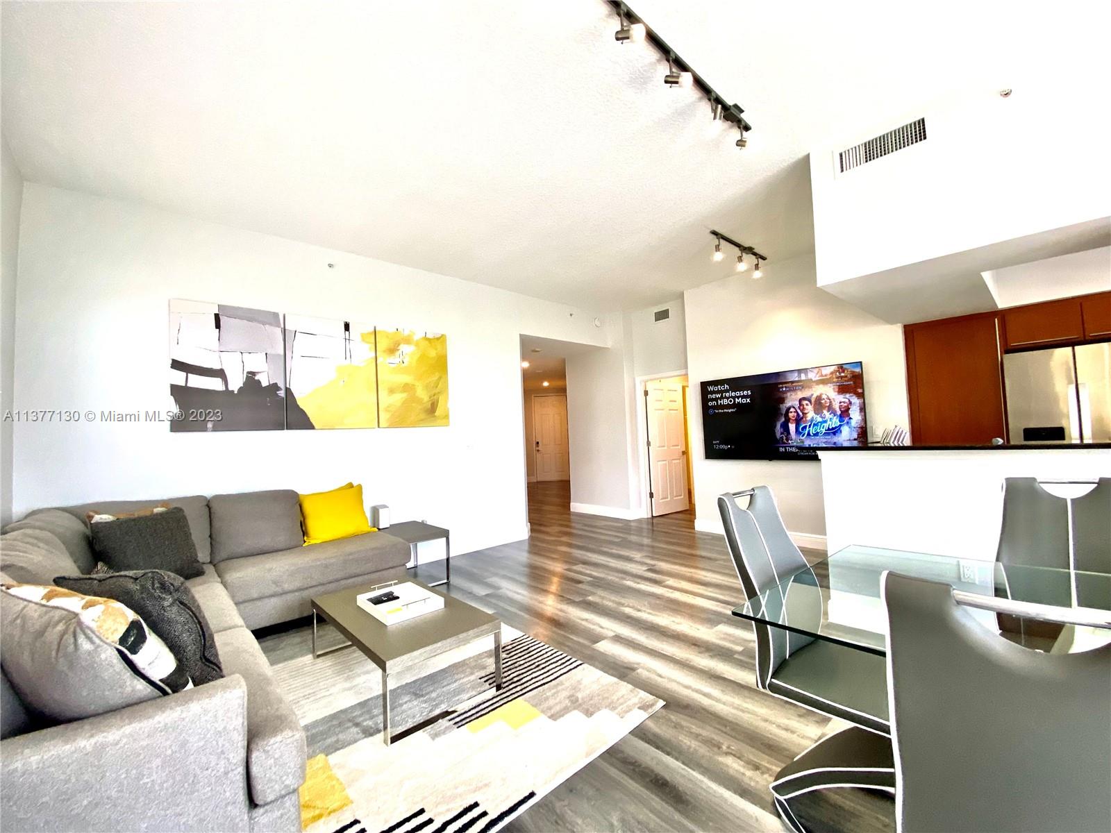 A living room features a grey sectional sofa, a glass dining table, and wood-look flooring — 2080 S Ocean Dr # 111, Hallandale Beach FL 33009, HALLANDALE BEACH, FL