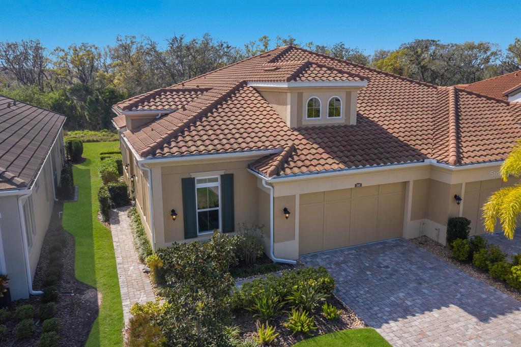 An aerial view of a tan house with a tiled roof and a paved driveway — 2402 STARWOOD COURT, LAKEWOOD RANCH, FL