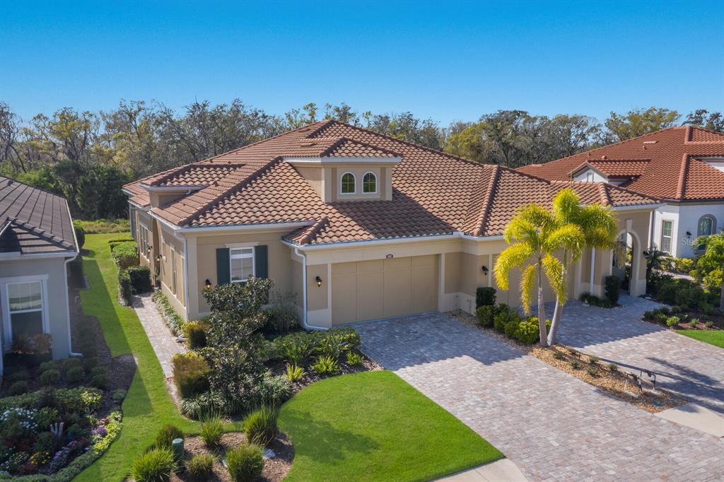 A single-story house with a beige exterior, a tiled roof, and a paved driveway — 2402 STARWOOD COURT, LAKEWOOD RANCH, FL