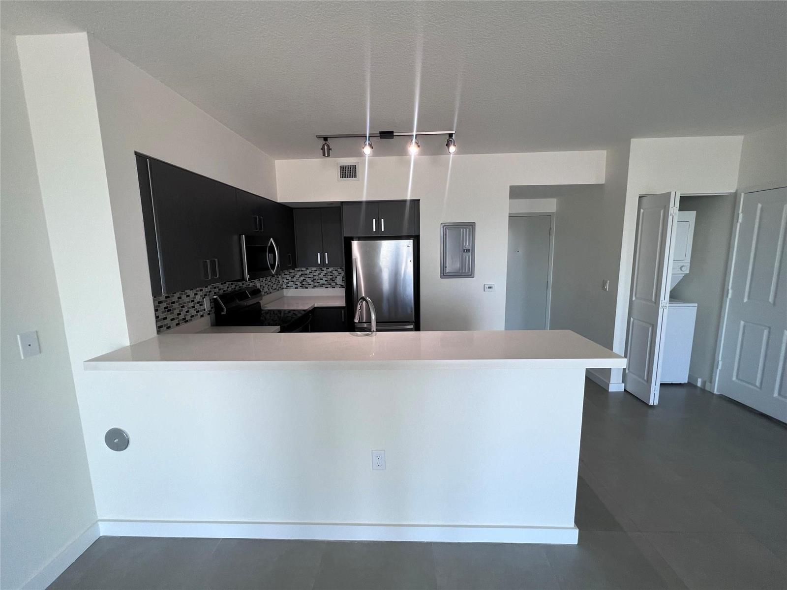 A kitchen features dark cabinets, stainless steel appliances, and a white breakfast bar — 729 NW 2 Street # 525, Miami FL 33128, MIAMI, FL