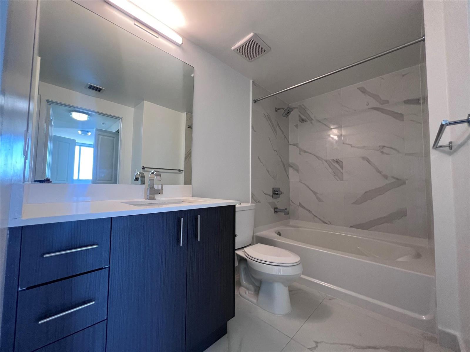 A bathroom features a dark wood vanity, white countertop, and a marble-tiled shower-tub combo — 729 NW 2 Street # 525, Miami FL 33128, MIAMI, FL