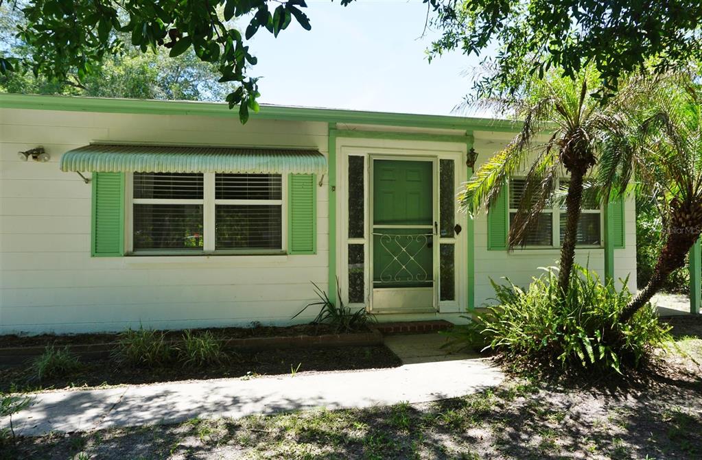 The exterior of a white house features green trim, window shutters, and a front door — 405 S CAMELLIA AVENUE, CRYSTAL RIVER, FL