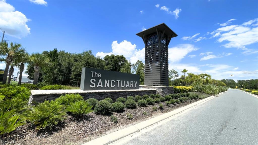A stone sign reading The Sanctuary stands next to a tall, dark wooden tower structure — 16308 WINDING PRESERVE CIRCLE, CLERMONT, FL