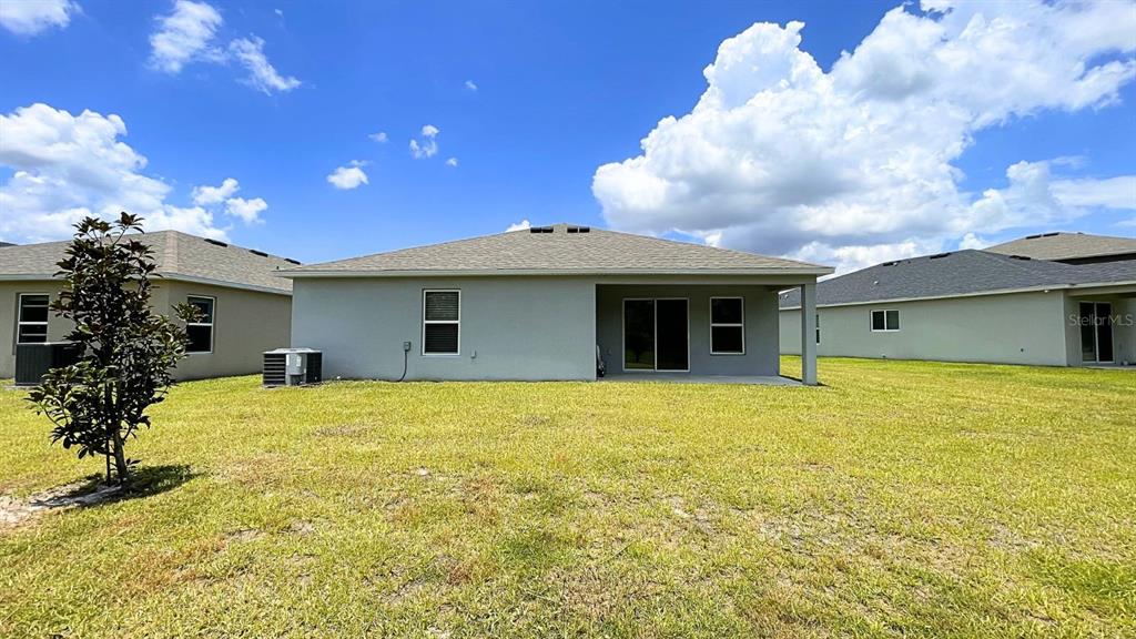 The exterior rear view of a single-story house features a covered patio and lawn — 16308 WINDING PRESERVE CIRCLE, CLERMONT, FL