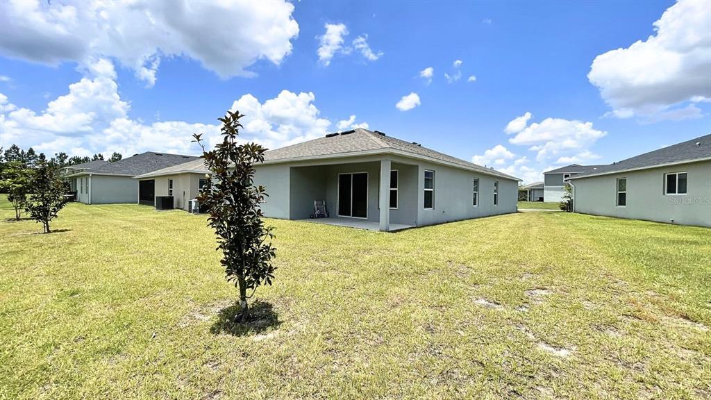 The exterior rear view of a single-story house features a covered patio and lawn — 16308 WINDING PRESERVE CIRCLE, CLERMONT, FL