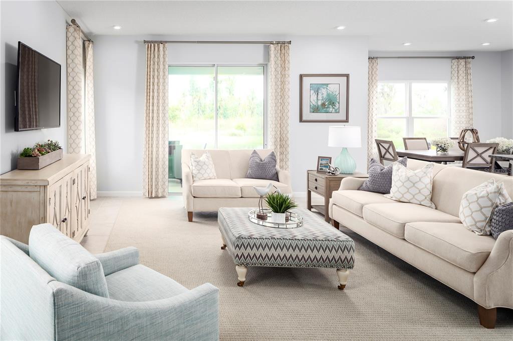 A bright living room features a beige sofa, a patterned ottoman, and light-colored furniture — 2439 WHITE LADYFISH ROAD, WIMAUMA, FL