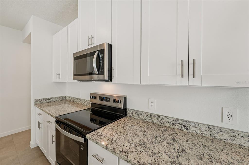 A kitchen features white cabinets, granite countertops, and stainless steel appliances — 104 WANDERING CREEK WAY, PALM COAST, FL