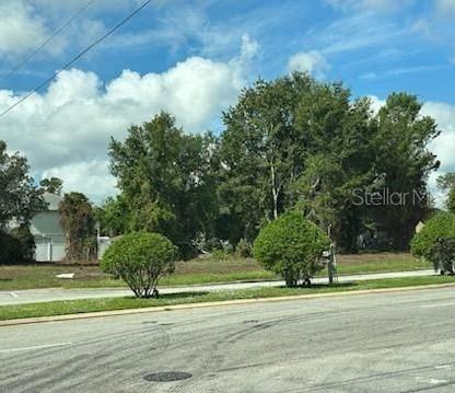 A vacant, grassy lot with several mature trees sits behind a paved road — 000 HOWLAND BLVD & BLUFFVIEW BOULEVARD, DELTONA, FL