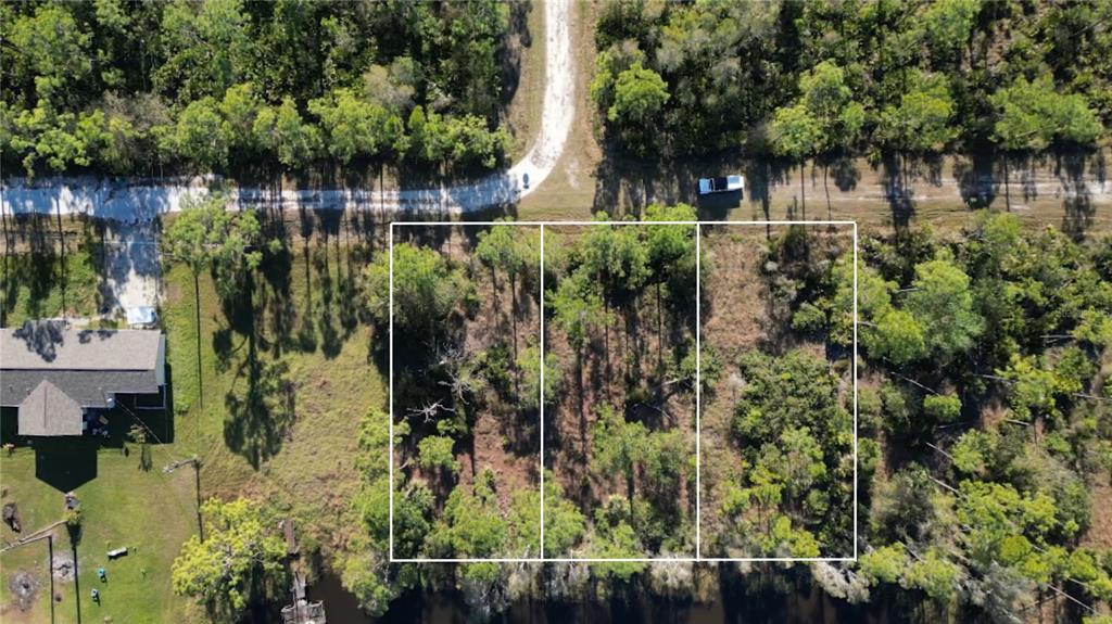 An aerial view shows three adjacent wooded lots bordering a body of water — 12135 LUDDEN COURT, PUNTA GORDA, FL