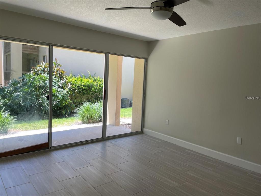 An empty room features light-colored tile flooring, a ceiling fan, and large sliding glass doors — 586 ORANGE DRIVE UNIT 118, ALTAMONTE SPRINGS, FL