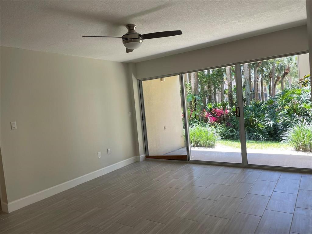 A room with light-colored tile flooring, a ceiling fan, and sliding glass doors to greenery — 586 ORANGE DRIVE UNIT 118, ALTAMONTE SPRINGS, FL