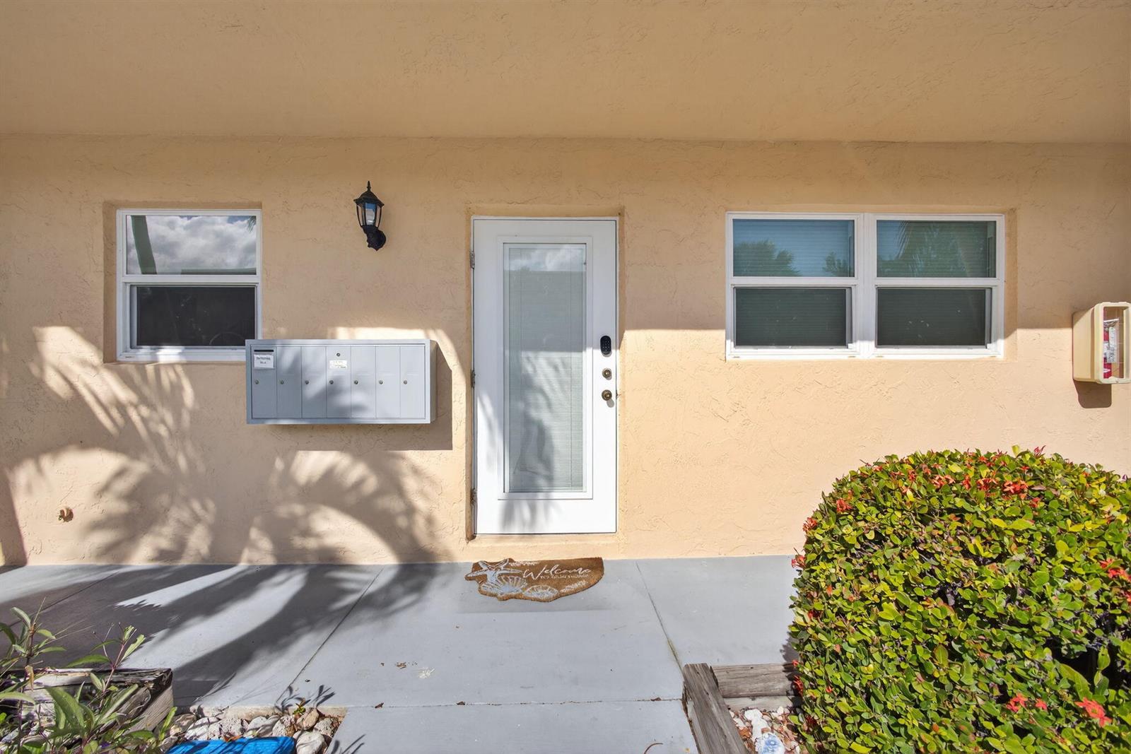 The exterior of a beige building features a central white door, windows, and mailboxes — 2950 SE Ocean Blvd Boulevard, Stuart FL 34996, STUART, FL