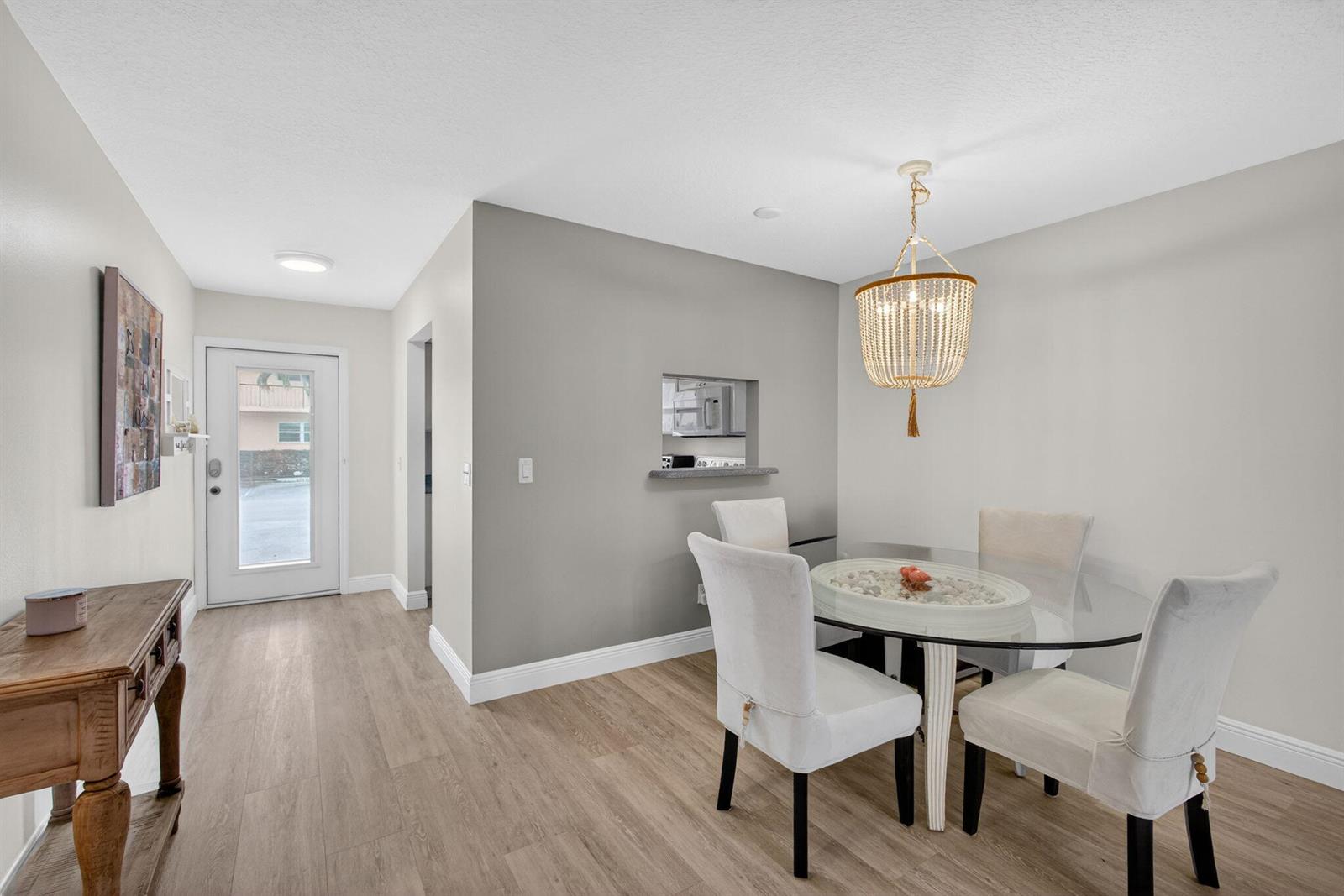 A dining area features a glass-topped table, upholstered chairs, a beaded chandelier, and wood flooring — 2950 SE Ocean Blvd Boulevard, Stuart FL 34996, STUART, FL