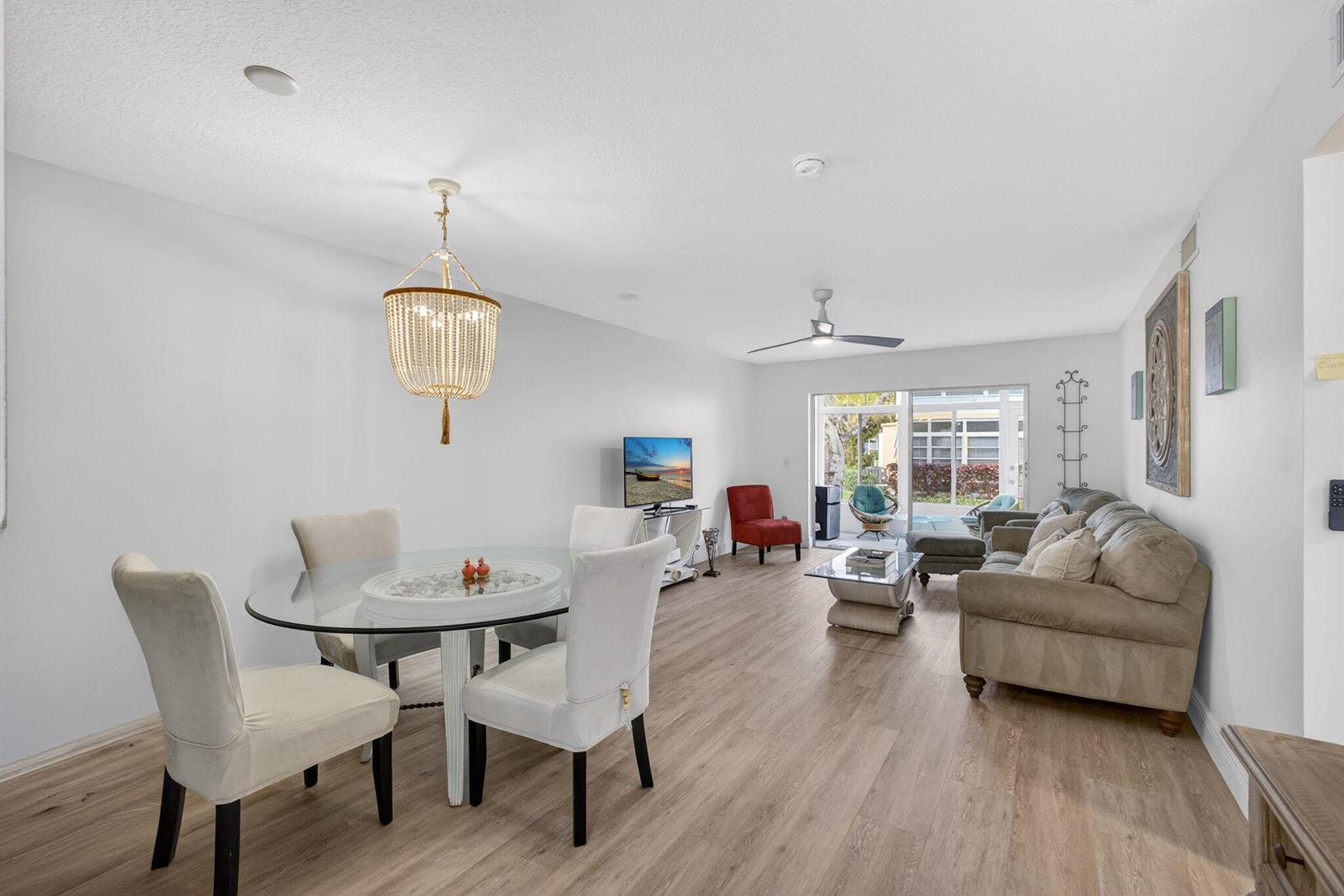 An open-concept living and dining area features light wood flooring, a glass table, and furniture — 2950 SE Ocean Blvd Boulevard, Stuart FL 34996, STUART, FL
