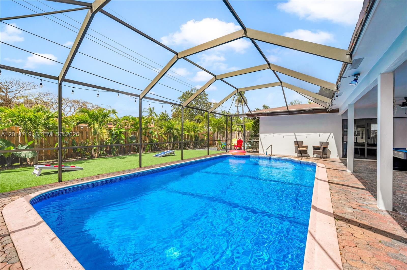 A screened-in swimming pool area features a patio, artificial turf, and a wooden fence — 1111 NW 70th Ter, Plantation FL 33313, PLANTATION, FL