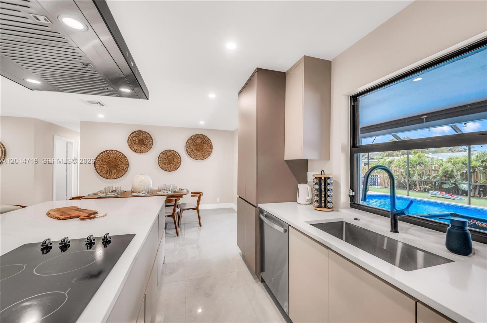 A modern kitchen features a large island, stainless steel appliances, and a view of a pool — 1111 NW 70th Ter, Plantation FL 33313, PLANTATION, FL