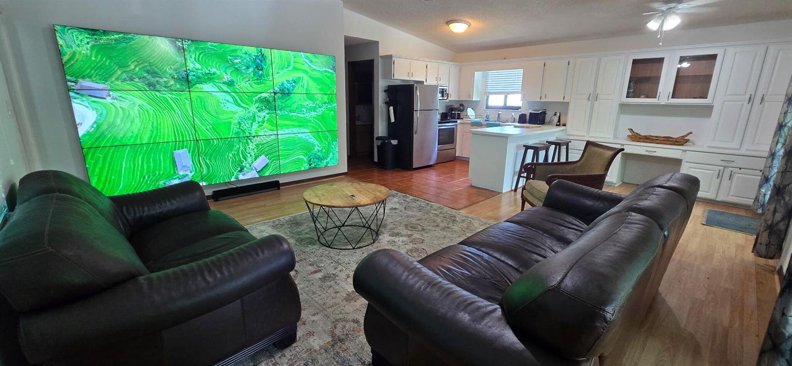 A living room with a large multi-panel wall display, leather sofas, and an open kitchen — 410 Coconut Drive, Key Largo FL 33037, KEY LARGO, FL