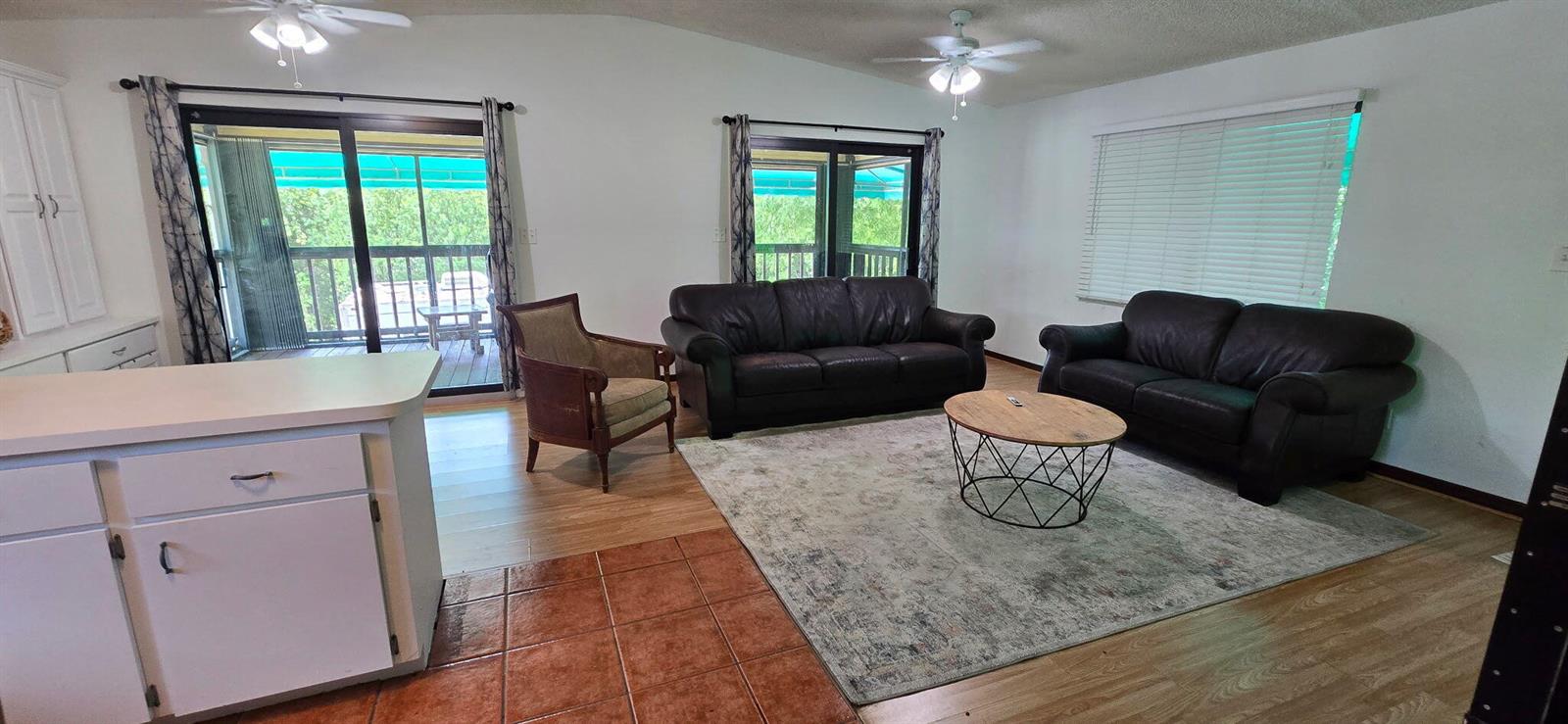 A living room features two dark leather sofas, a wood coffee table, and sliding doors — 410 Coconut Drive, Key Largo FL 33037, KEY LARGO, FL