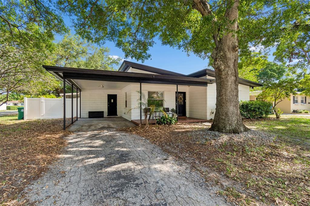 A single-story white house with a carport, a front porch, and a large tree — 4602 W BAY VILLA AVENUE, TAMPA, FL
