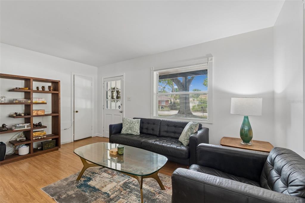 A living room features a black leather sofa, a glass coffee table, and a wooden bookshelf — 4602 W BAY VILLA AVENUE, TAMPA, FL