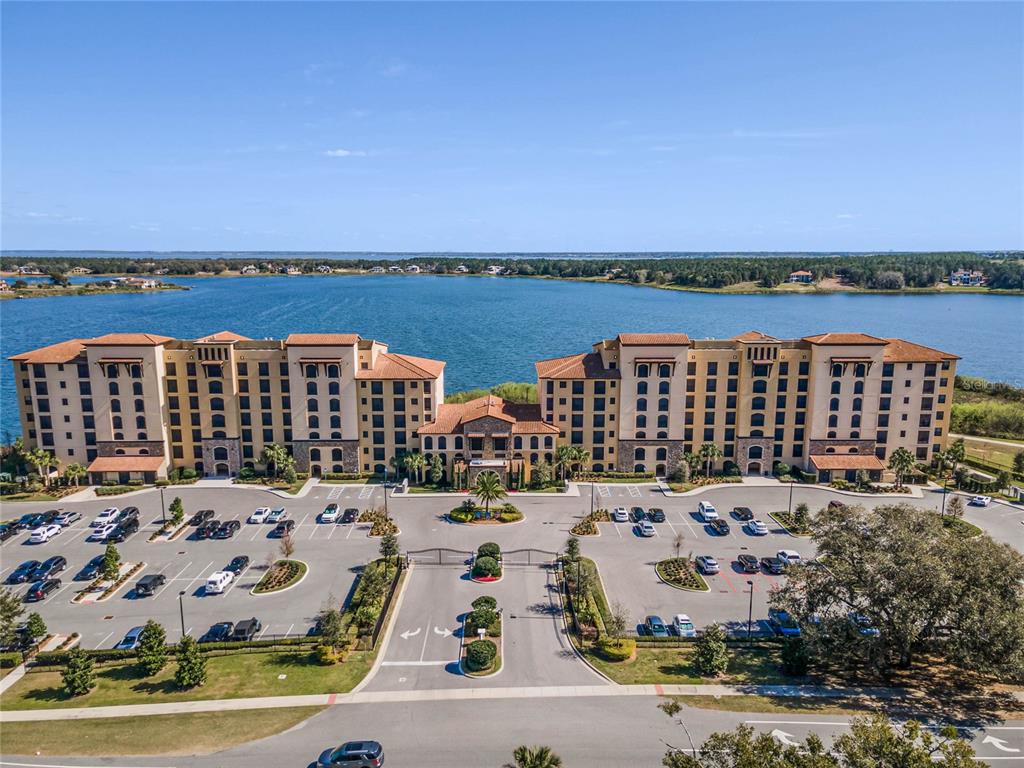 An aerial view shows a large multi-story apartment complex situated along a lakefront — 16300 COUNTY ROAD 455 UNIT 305, MONTVERDE, FL