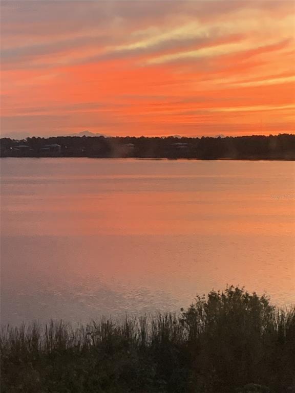 A vibrant sunset glows over a calm lake with a dark treeline in the distance — 16300 COUNTY ROAD 455 UNIT 305, MONTVERDE, FL