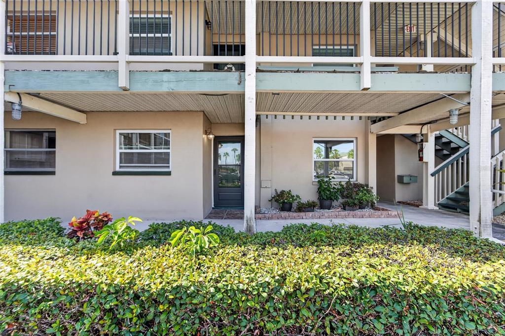 The exterior of a multi-story apartment building features a ground-level entrance, stairs, and landscaping — 1028 APOLLO BEACH BOULEVARD UNIT 104, APOLLO BEACH, FL