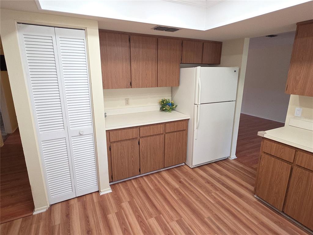 A kitchen features wood-grain cabinets, white countertops, a white refrigerator, and wood-look flooring — 6264 DARIEN WAY, SPRING HILL, FL