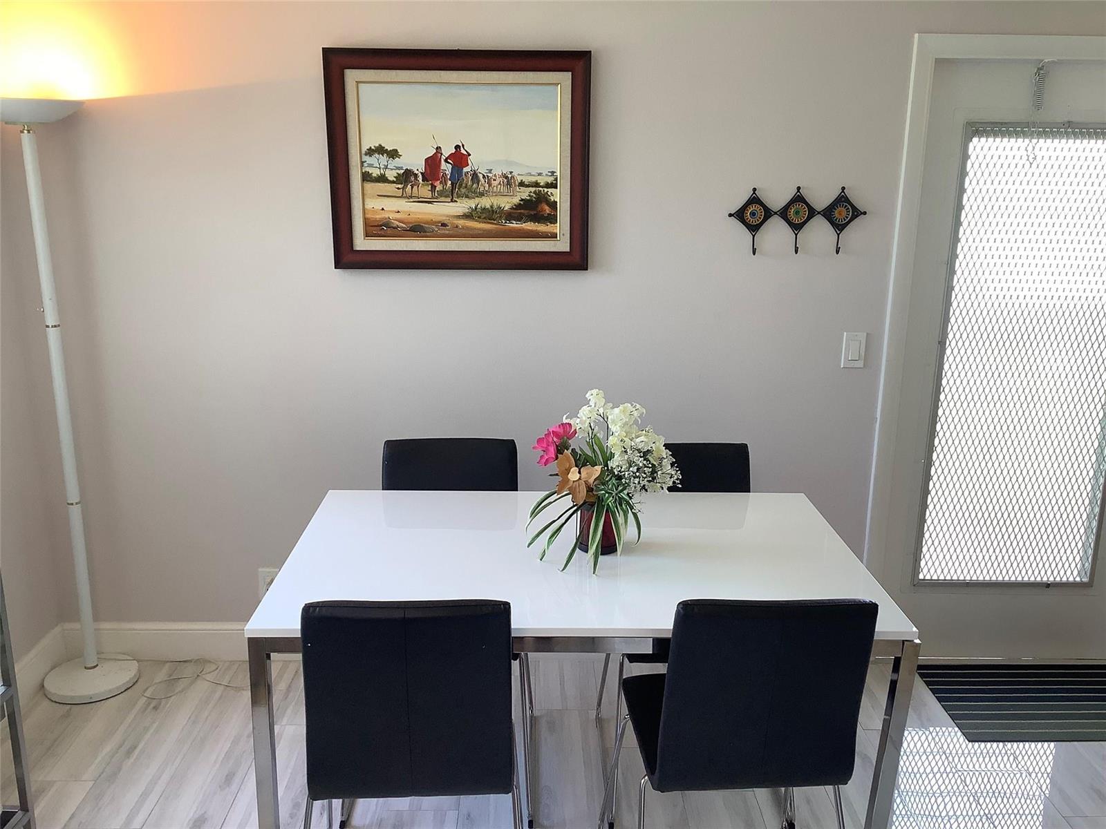 A dining room features a white table, four black chairs, a painting, and a floor lamp — 364 Dorset I # 364, Boca Raton FL 33434, BOCA RATON, FL