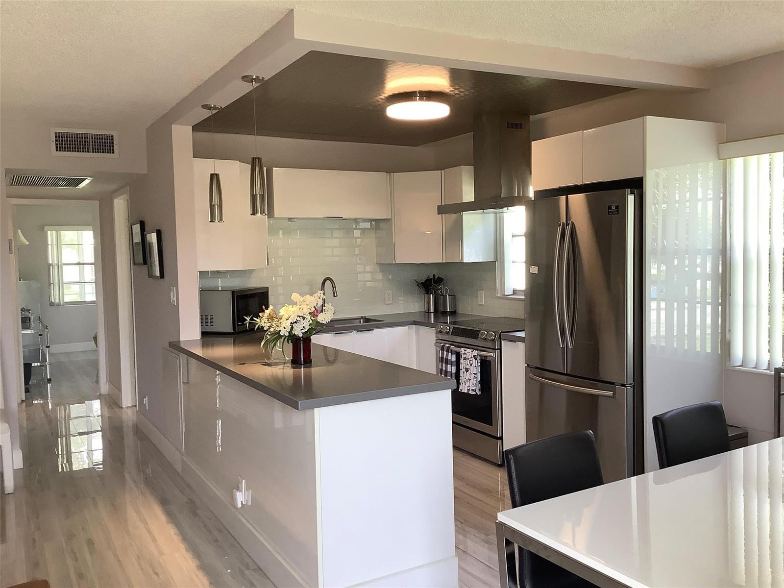 A modern kitchen features white cabinets, stainless steel appliances, and a gray countertop island — 364 Dorset I # 364, Boca Raton FL 33434, BOCA RATON, FL