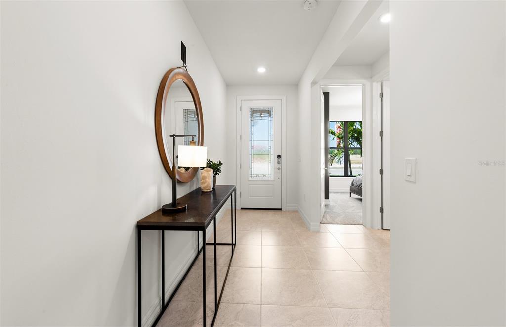 A bright entryway features a console table, a round mirror, and tile flooring — 2712 WINDING CREEK TRAIL, NORTH PORT, FL