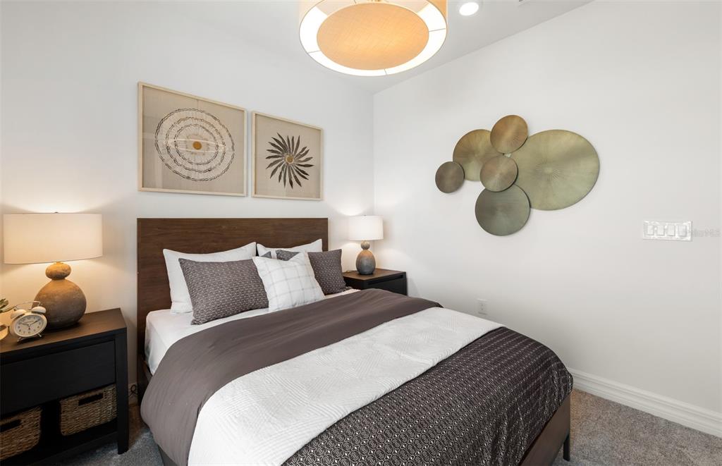 A bedroom features a dark wood bed frame, two nightstands, and wall-mounted circular metal art — 2712 WINDING CREEK TRAIL, NORTH PORT, FL
