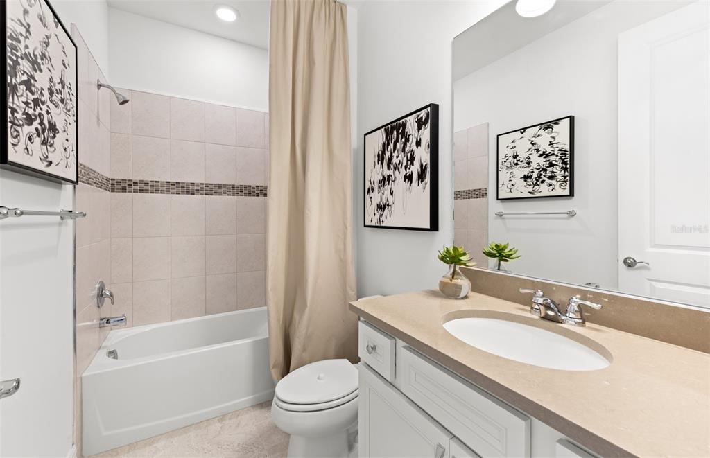 A bathroom features a white vanity, a toilet, and a shower-tub combination with beige tiles — 2712 WINDING CREEK TRAIL, NORTH PORT, FL