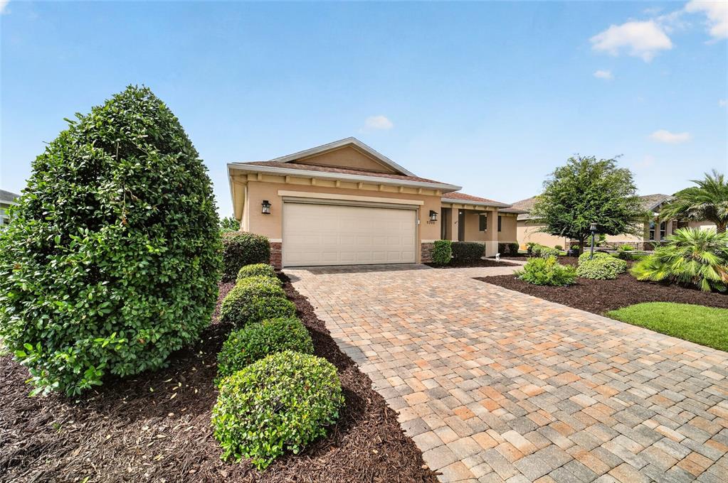 A tan single-story house features a two-car garage and a paved driveway with landscaping — 9200 SW 85TH PLACE, OCALA, FL