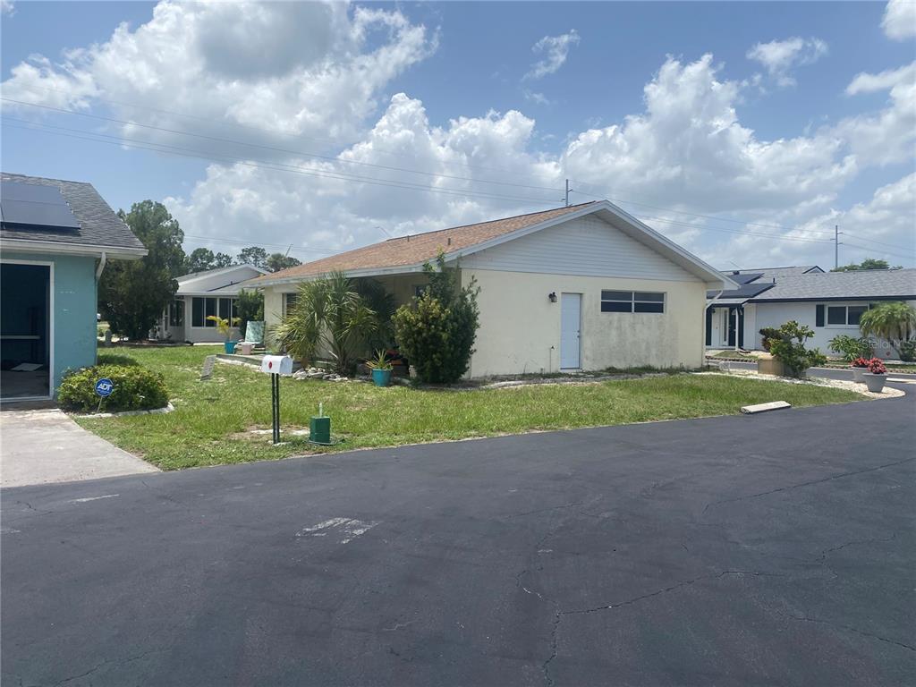 A light-colored, single-story house with a brown roof sits next to a paved driveway — 703 HUXLEY PLACE, SUN CITY CENTER, FL