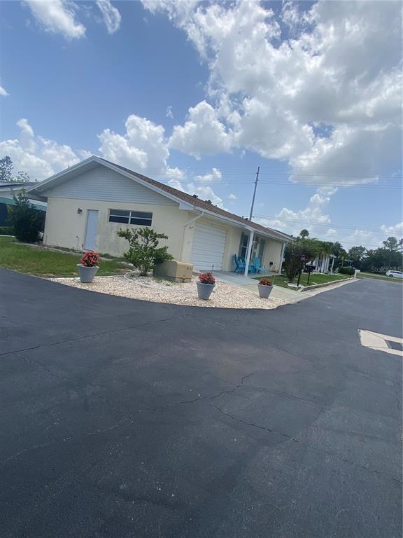 A single-story house with a garage, light-colored siding, and three potted plants in front — 703 HUXLEY PLACE, SUN CITY CENTER, FL