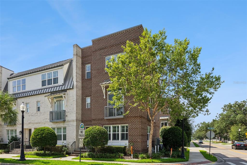 A three-story brick townhouse with balconies and a sidewalk along a street — 484 W PLANT STREET, WINTER GARDEN, FL