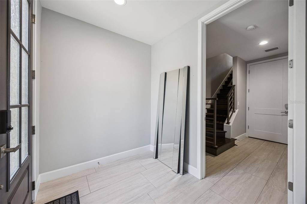 An entryway features light tile flooring, a large leaning mirror, and a view of stairs — 484 W PLANT STREET, WINTER GARDEN, FL