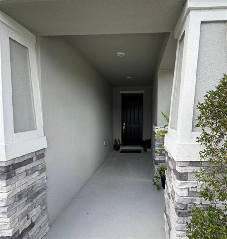 A covered entryway features stone-clad columns, a light gray concrete floor, and a dark front door — 139 PERSHING ST, BARTOW, FL