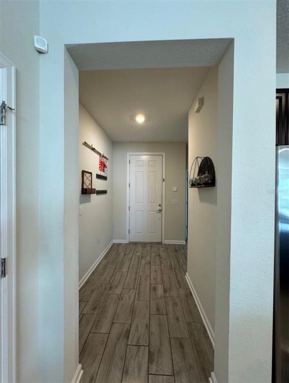 A view through a doorway into a foyer with wood-look tile flooring and a door — 139 PERSHING ST, BARTOW, FL