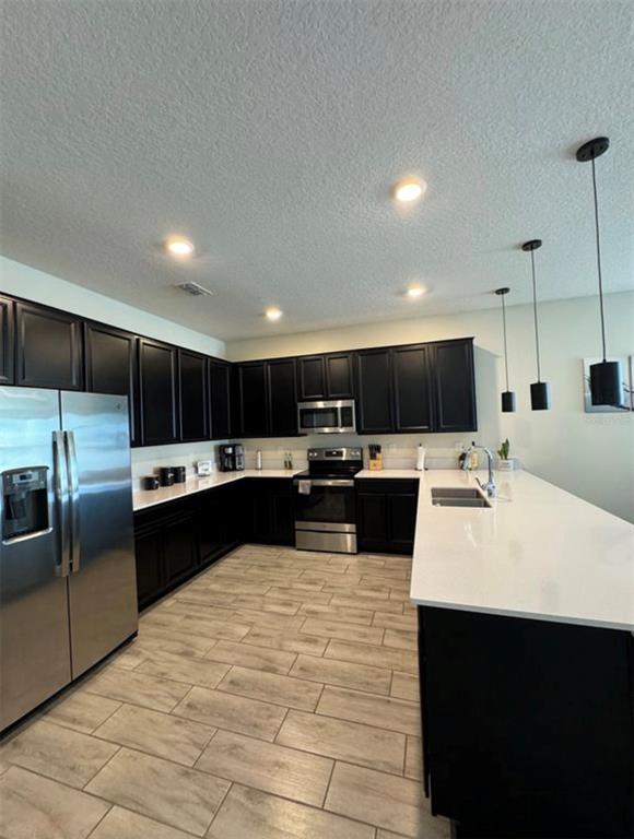 A modern kitchen features black cabinets, white countertops, stainless steel appliances, and light-colored tile flooring — 139 PERSHING ST, BARTOW, FL