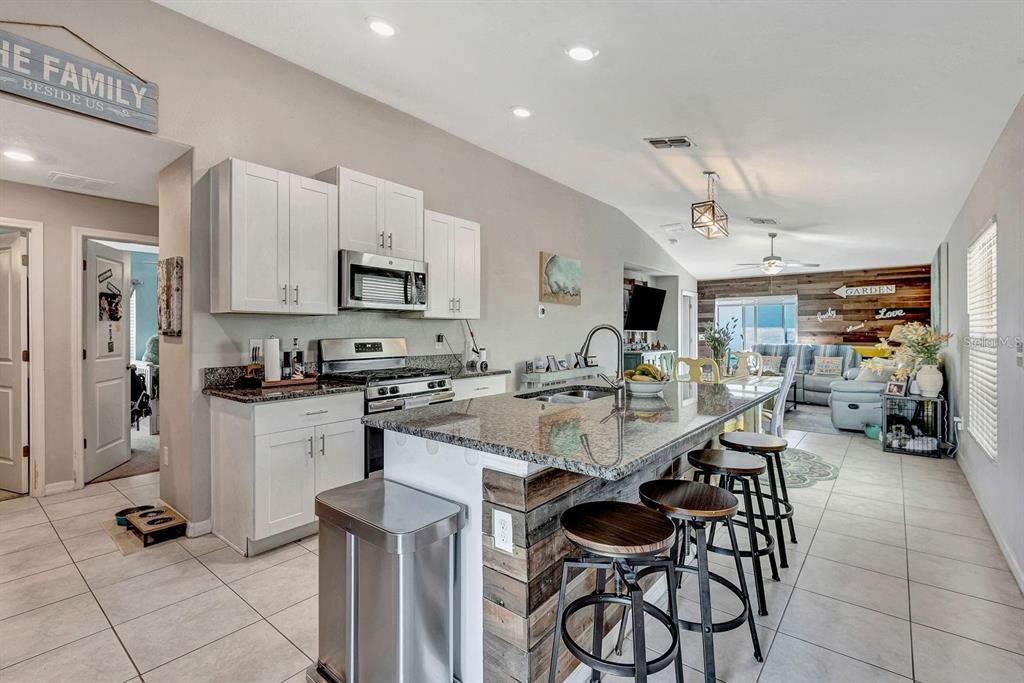 A kitchen with white cabinets, granite countertops, and a wood-paneled island with bar stools — 5104 DANDELION STREET, APOLLO BEACH, FL