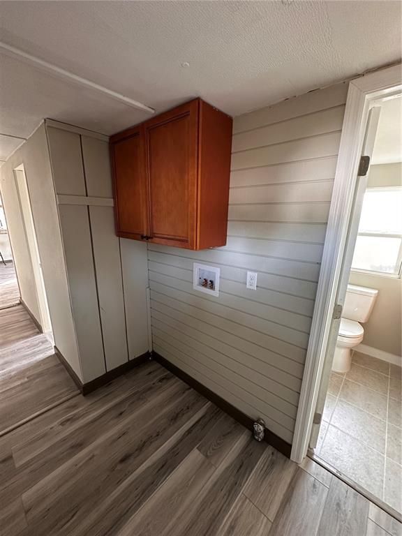 A laundry area features wood-look flooring, shiplap walls, wall-mounted cabinets, and a washer hookup box — 16083 NAPLES STREET, BROOKSVILLE, FL