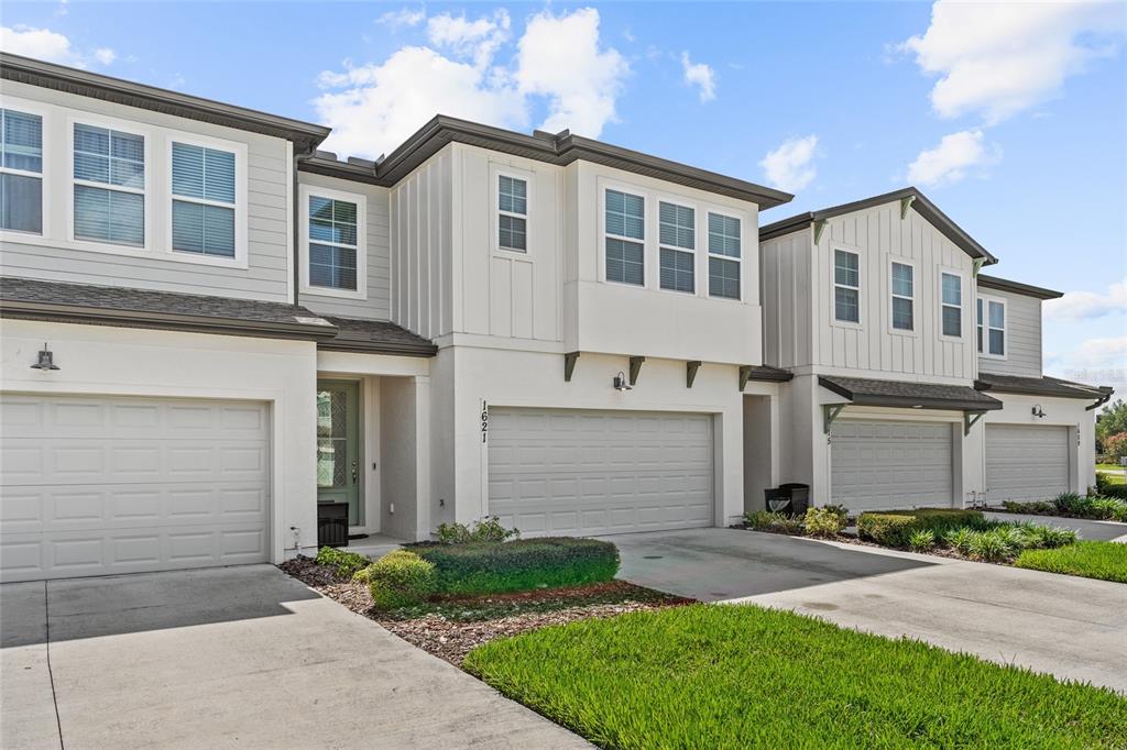 A row of modern two-story townhomes features light-colored siding, attached garages, and concrete driveways — 1621 SANIBEL DRIVE, DAVENPORT, FL