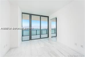 A bright, minimalist room features white marble floors, floor-to-ceiling windows, and a water view — 480 NE 31 ST # 2306, Miami FL 33137, MIAMI, FL