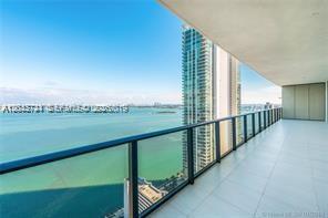 A high-rise balcony features a glass railing overlooking a large body of water and city — 480 NE 31 ST # 2306, Miami FL 33137, MIAMI, FL