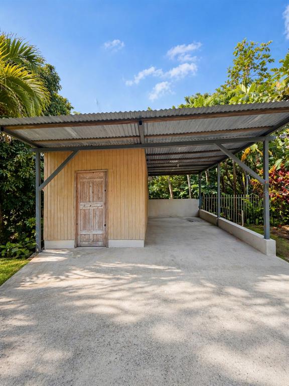 A detached wooden storage shed with an attached metal-roofed carport on a concrete driveway — R517 COLLORES WARD, JUANA DIAZ, PR