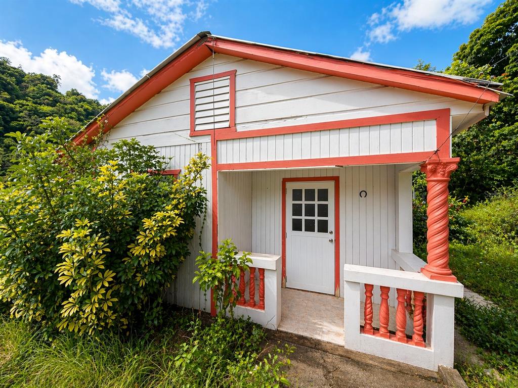 A small white house with orange trim and a covered porch featuring a spiral column — R517 COLLORES WARD, JUANA DIAZ, PR