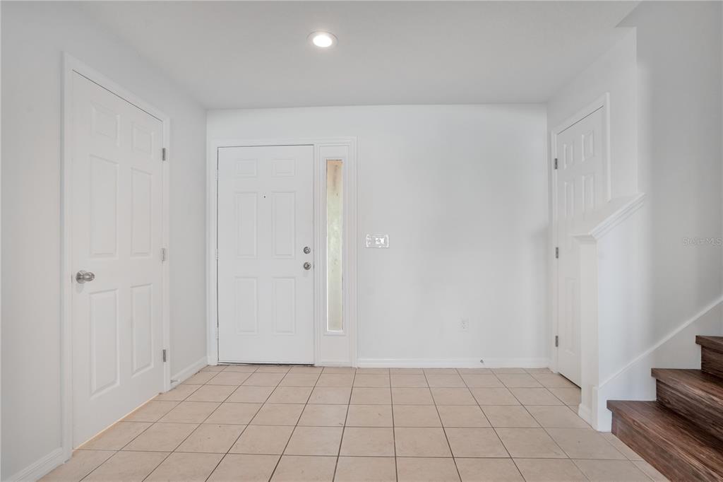 An entryway features white walls, tiled flooring, a front door with a sidelight, and stairs — 12012 CITRUS LEAF DRIVE, GIBSONTON, FL