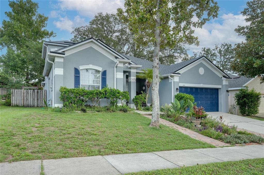 A single-story gray house with blue shutters and a blue garage door sits on a lawn — 2474 CIMMARON ASH WAY, APOPKA, FL